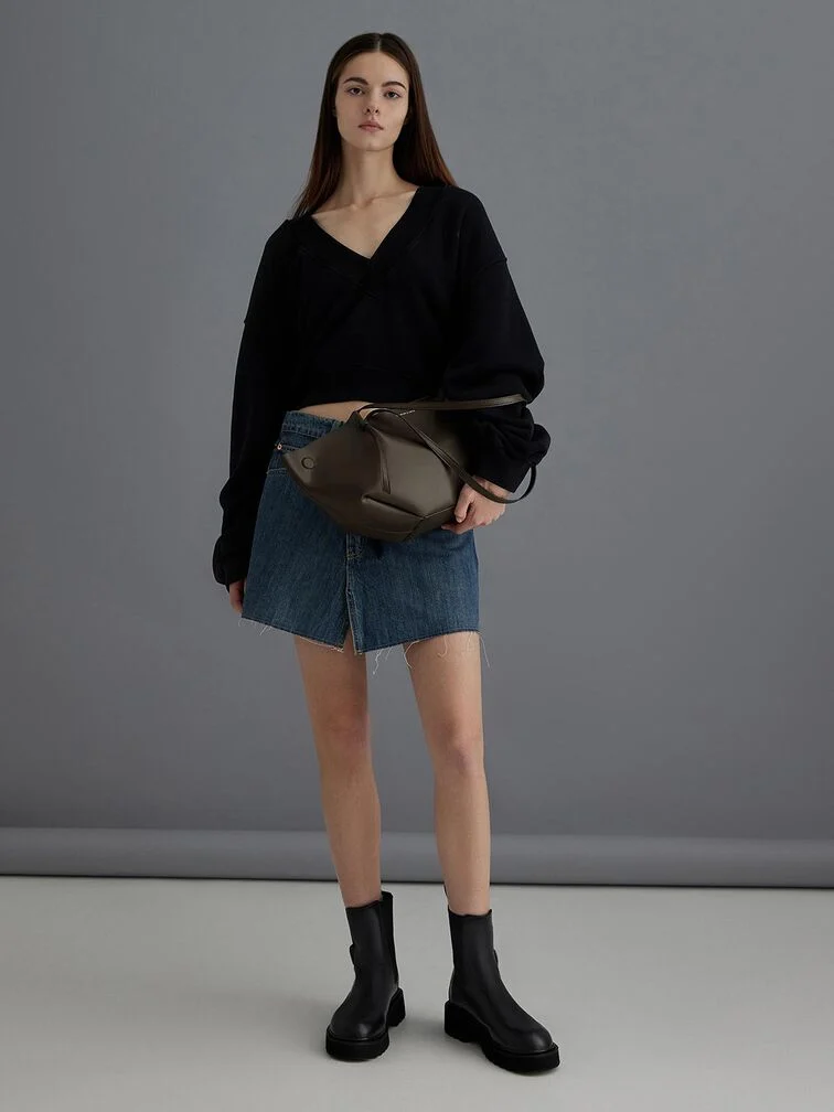 The Calla tote bag in dark moss styled with a knit top and denim skirt for a casual, everyday look. 